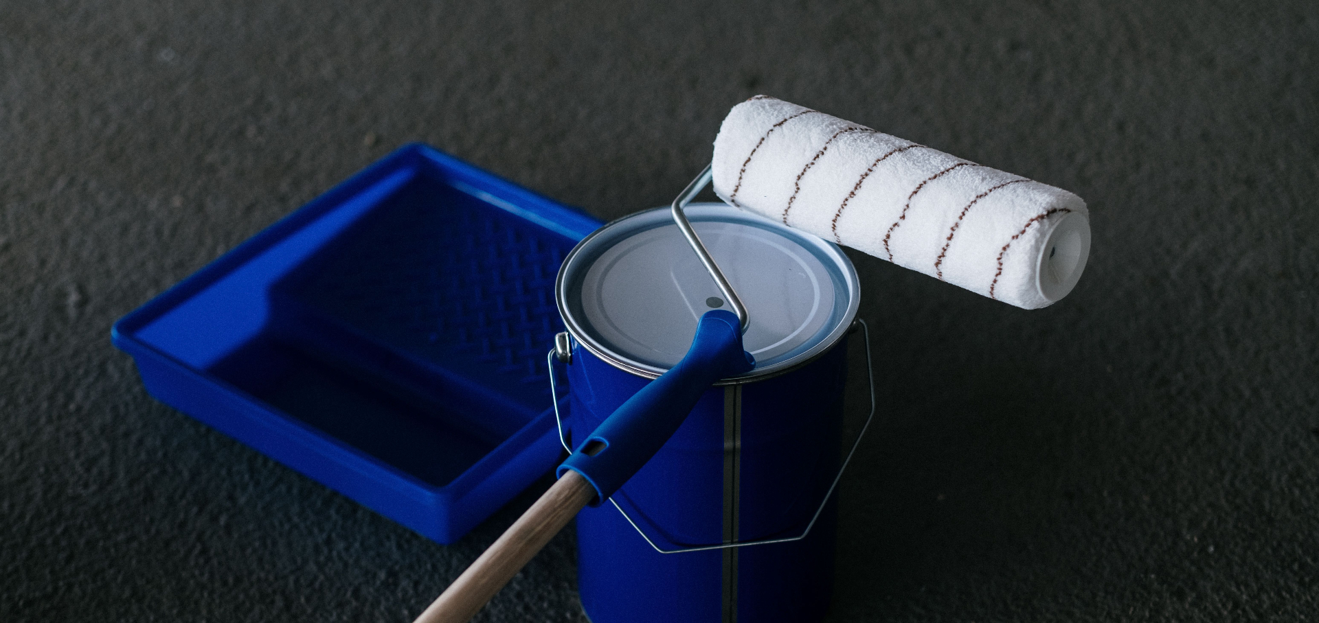 Blue paint can with roller and tray ready for a professional painting service