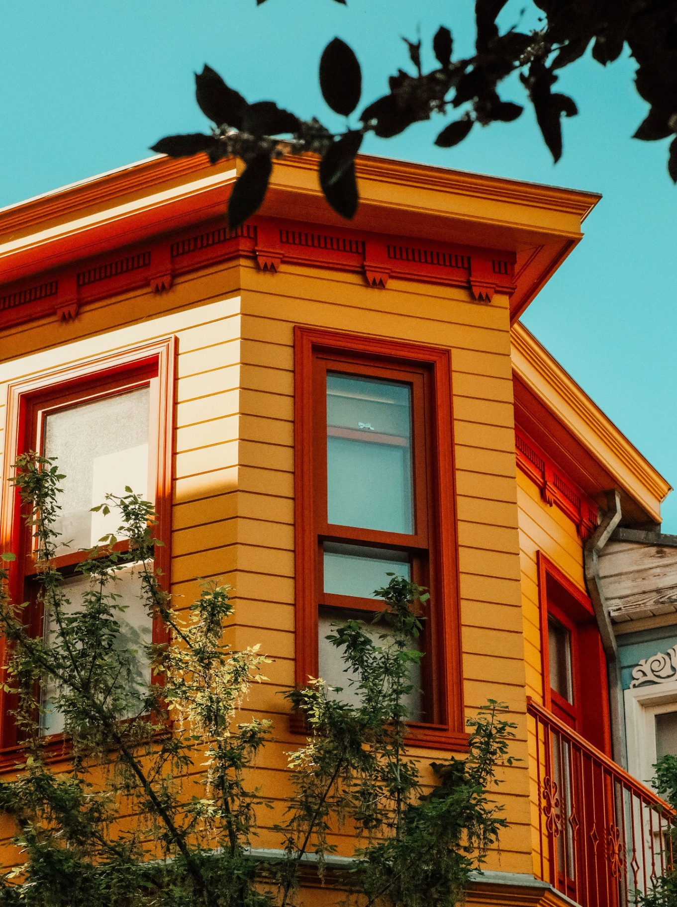 Warm, sunlit Victorian home exterior with detailed trim painted in rich amber tones